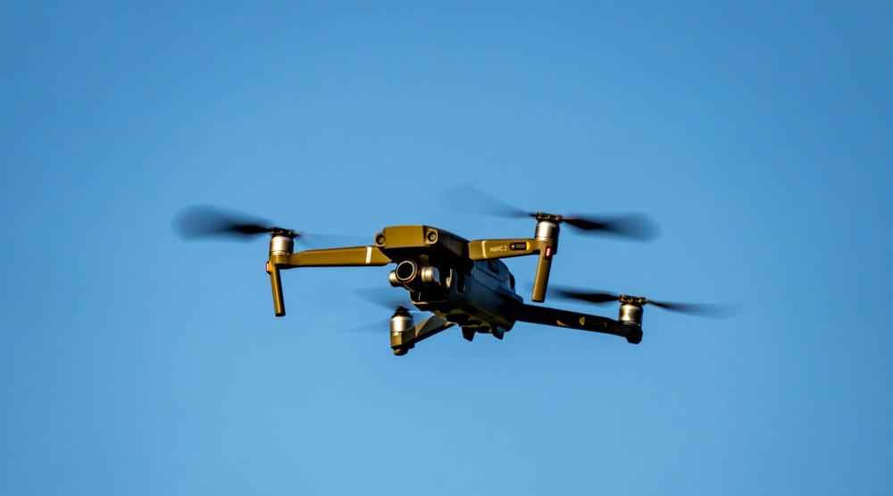 Lecący dron na tle niebieskiego nieba